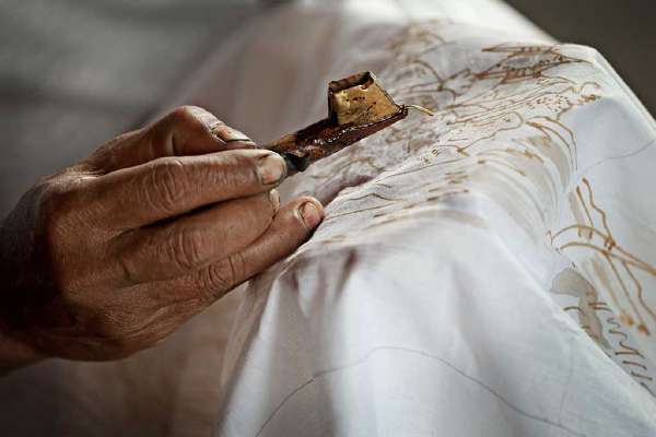 Close up of a Batik artist painting on a white cloth, Indonesia
